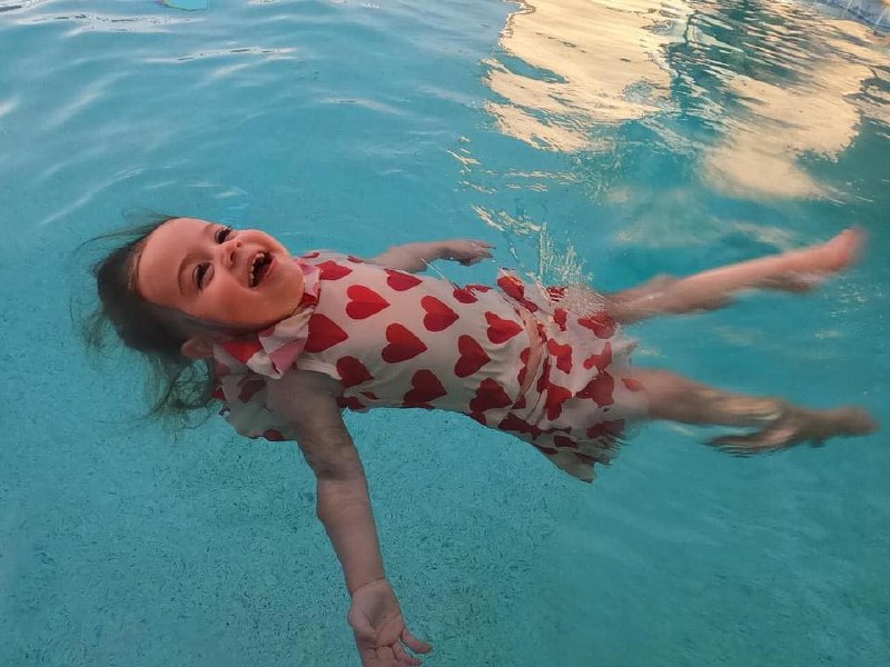 Baby in heart swimsuit demonstrating float skills