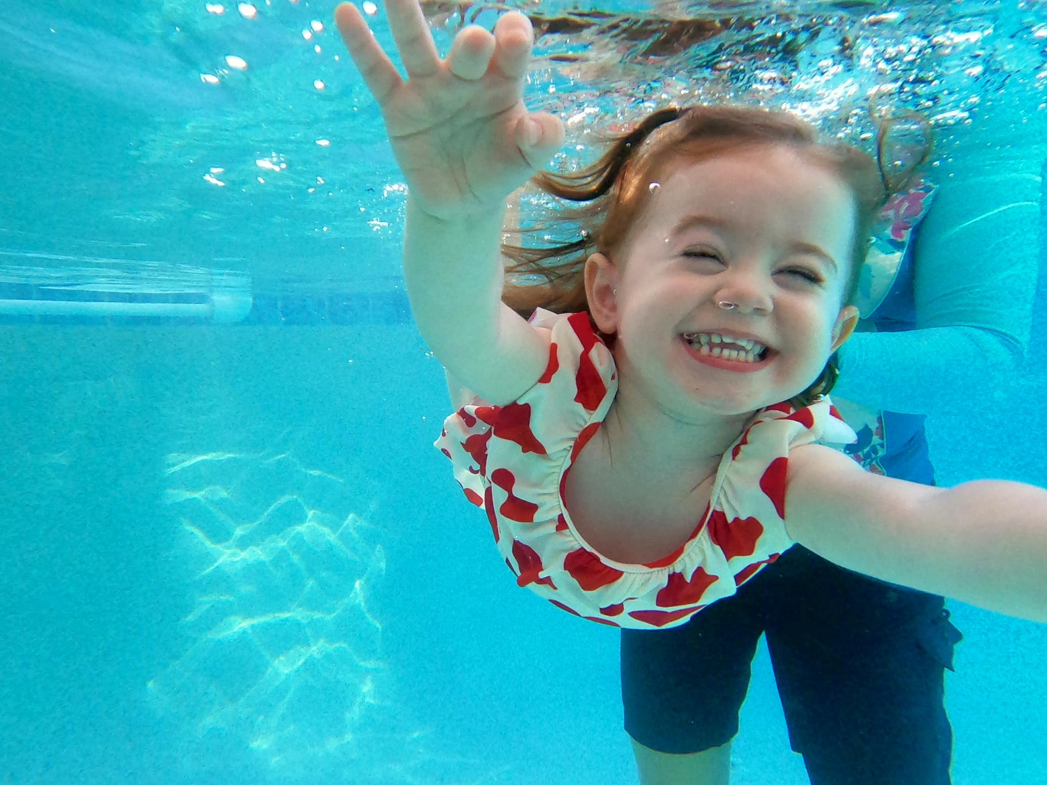 Smiling girl underwater in a hearts swimsuit during ISR lesson